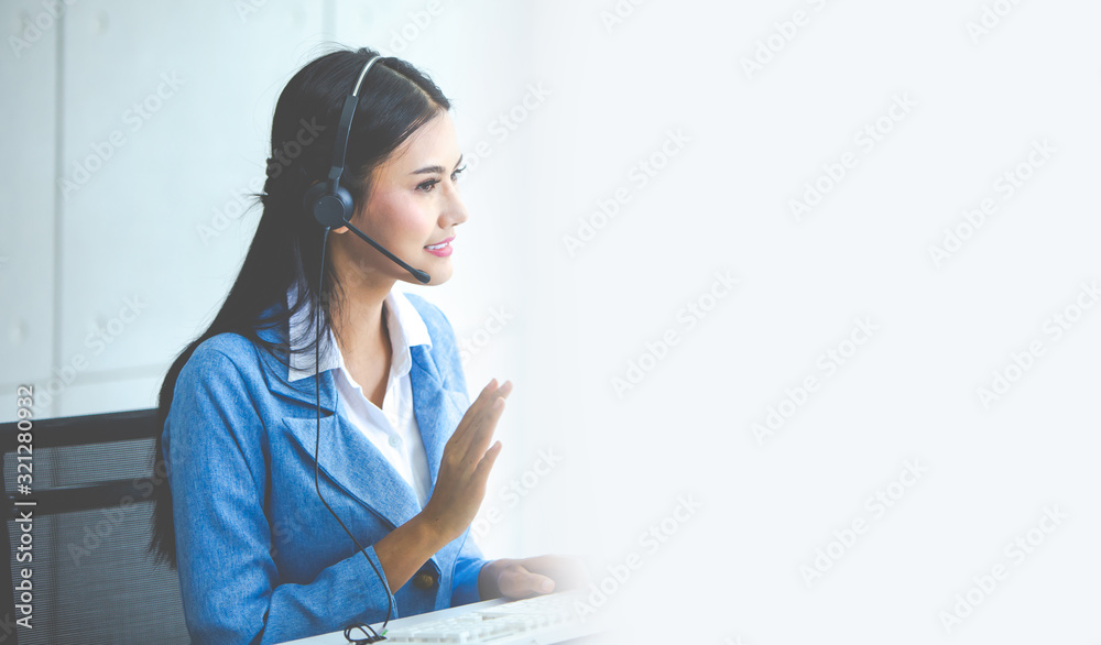 Attractive business woman Asian in suits and headsets are smiling while working with computer at office. Customer service assistant working in office