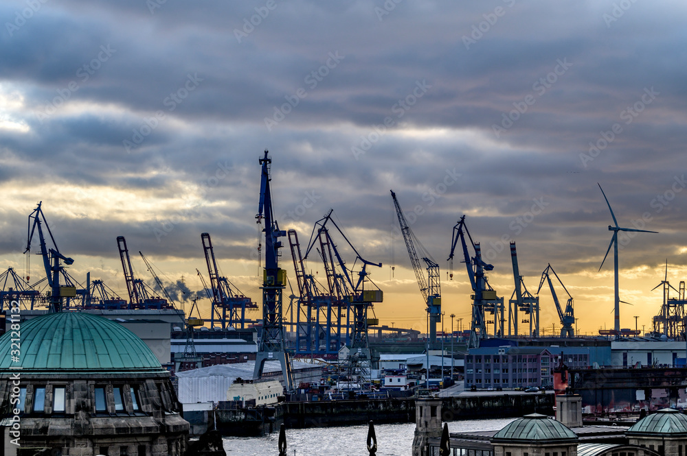 Der Hamburger Hafen am Abend mit Hafenkränen und Windrädern  im Gegenlicht