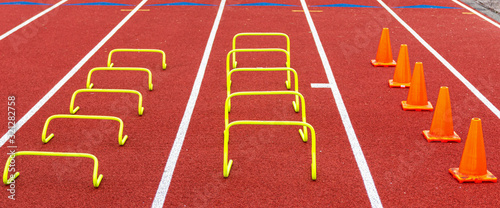 Mini hurdles and cones set up in lanes on a track for speed and agility practice