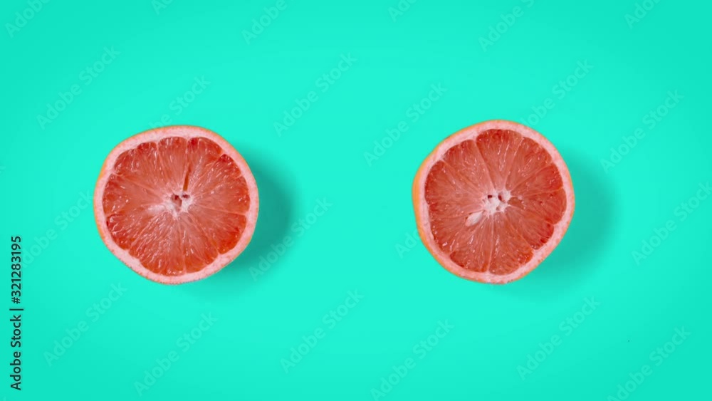 Stop motion animation Top view on two halves grapefruit rotating or dancing on cyan aqua menthe color background. Seamless loop. Real fruits. 4k