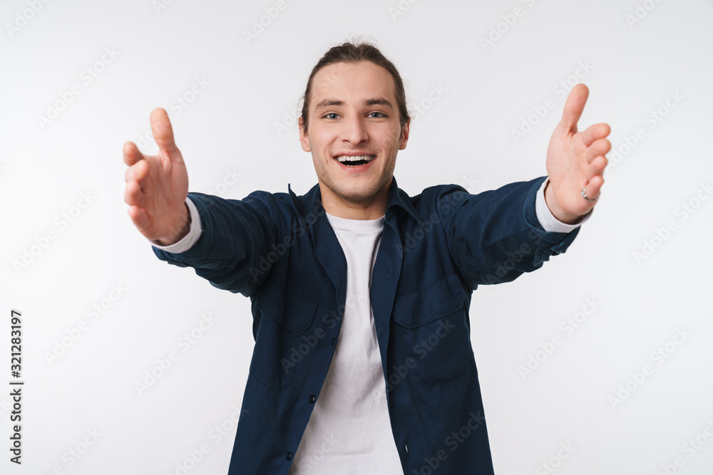 Image of happy young man smiling and pulling his hands to camera Image of happy young man smiling and pulling his hands to camera