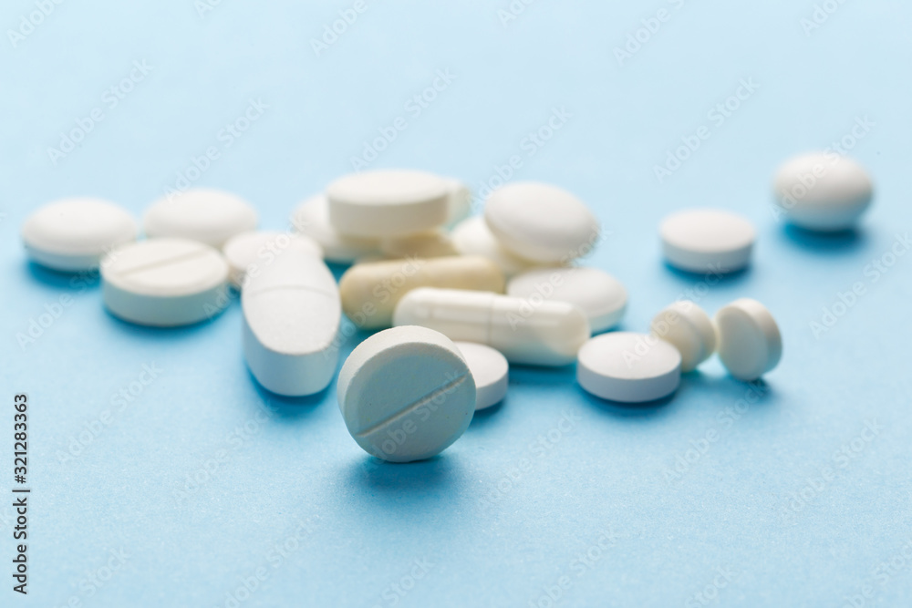 scattered white pills on a blue table. Layout for special offers such as advertising or other ideas. The concept of medicine, pharmacy and healthcare. Space for copy. flat lay for text or logo. scattered white pills on a blue table. Layout for special offers such as advertising or other ideas. The concept of medicine, pharmacy and healthcare. Space for copy. flat lay for text or logo.
