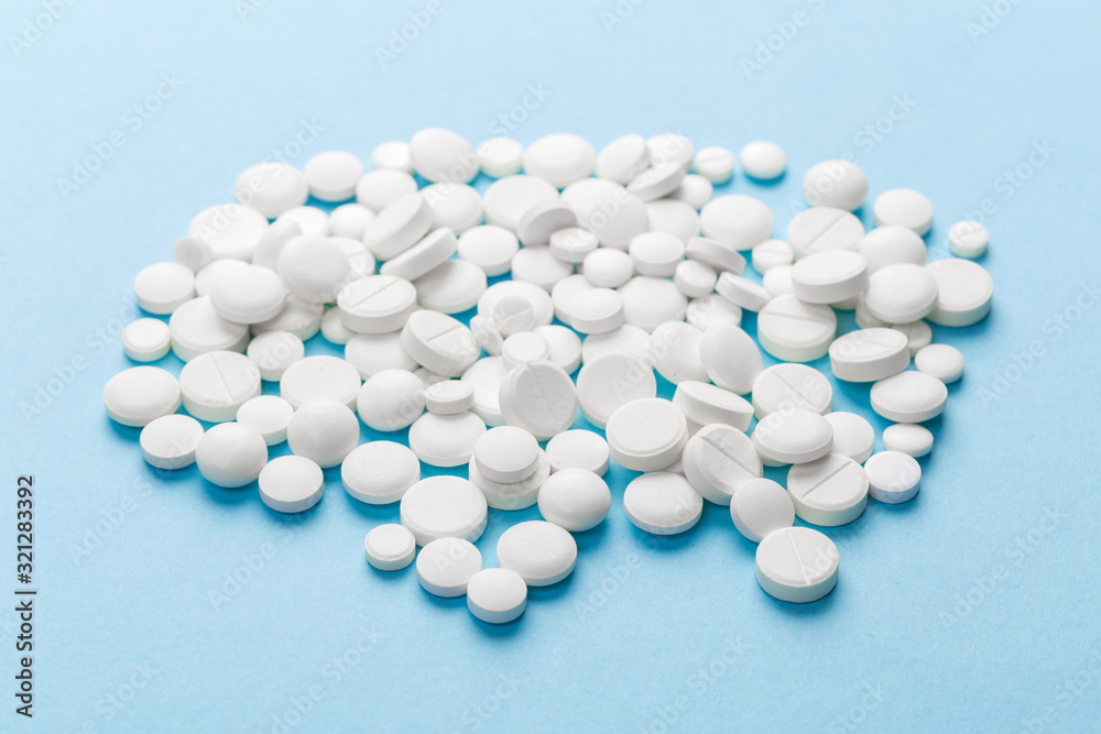 scattered white pills on a blue table. Layout for special offers such as advertising or other ideas. The concept of medicine, pharmacy and healthcare. Space for copy. flat lay for text or logo. scattered white pills on a blue table. Layout for special offers such as advertising or other ideas. The concept of medicine, pharmacy and healthcare. Space for copy. flat lay for text or logo.