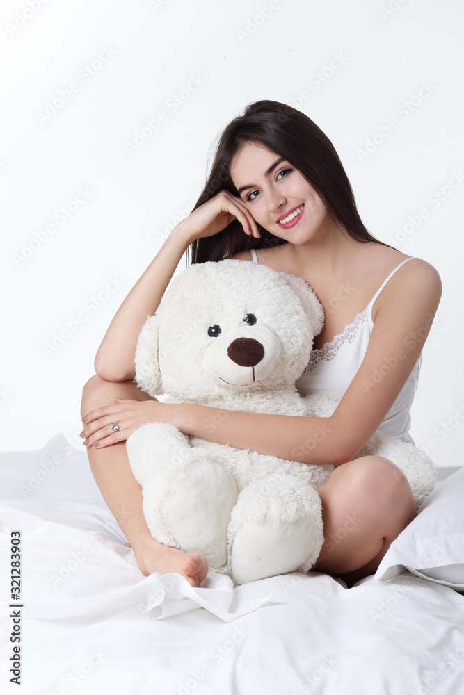 Young woman smile face with teddy close up while lying on the bed