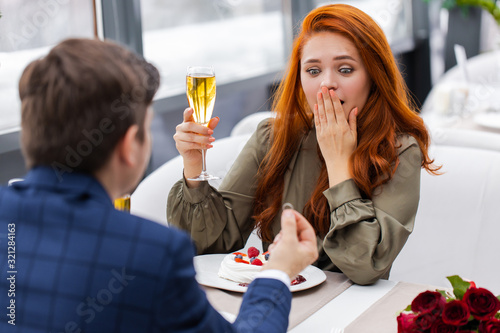 redhaired caucasian lady and handsome gentleman in restaurant, spend time together, woman and man in love, making marriage proposal during dinner in the evening. love concept
