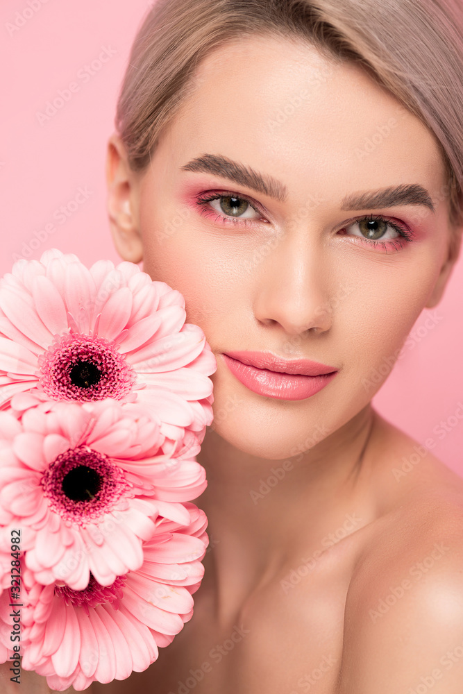 beautiful young woman with pink gerbera flowers, isolated on pink