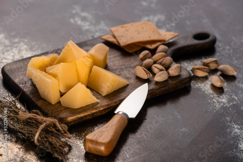 cheese platter with Grana Padano, crackers and pistachios near knife