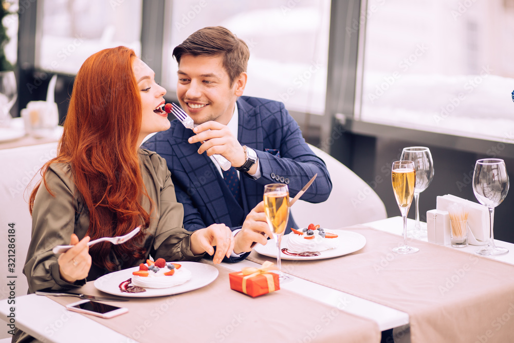 couple sit in restaurant together. couple celebrating anniversary, spend romantic day in rich restaurant. careful handsome guy in elegant stylish tux treats his girlfriend with tasty sweet dessert couple sit in restaurant together. couple celebrating anniversary, spend romantic day in rich restaurant. careful handsome guy in elegant stylish tux treats his girlfriend with tasty sweet dessert