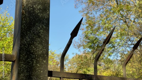 POV walk along garden wrought iron black spiked fence on a sunny autumn day.