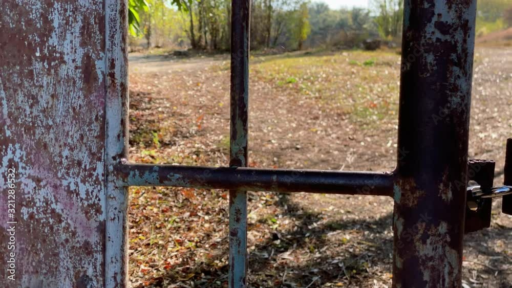 Locked padlock on rusty metal gate on a sunny autumn day. Locked padlock on rusty metal gate on a sunny autumn day.