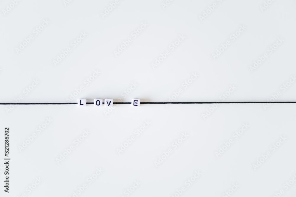 Love word made from letters printing blocks on a black rope. White background Love word made from letters printing blocks on a black rope. White background