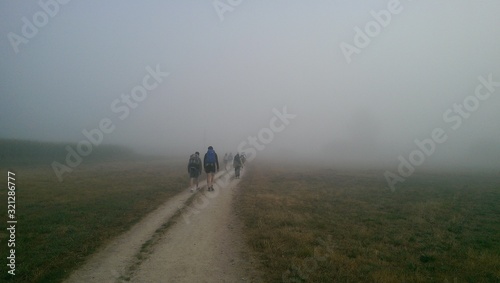 Pilgrims walking on a foggy road on the way of St James, Pilgrimage of Compostela, camino de santiago.