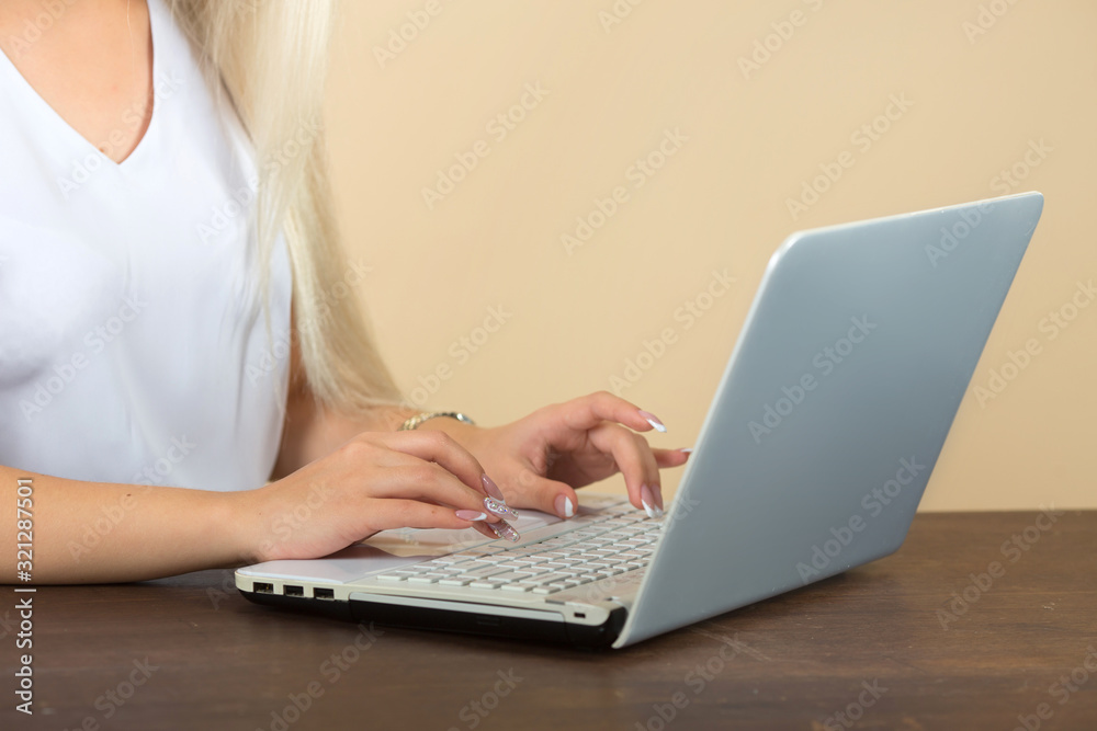 Fototapeta premium woman working on a laptop on a beige background