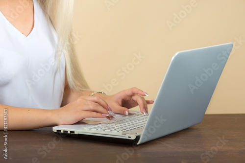 woman working on a laptop on a beige background