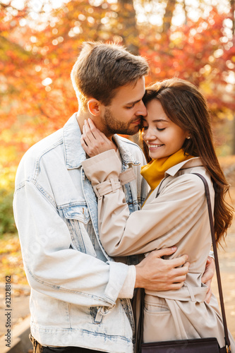 Image of attractive young caucasian couple walking through autumn park