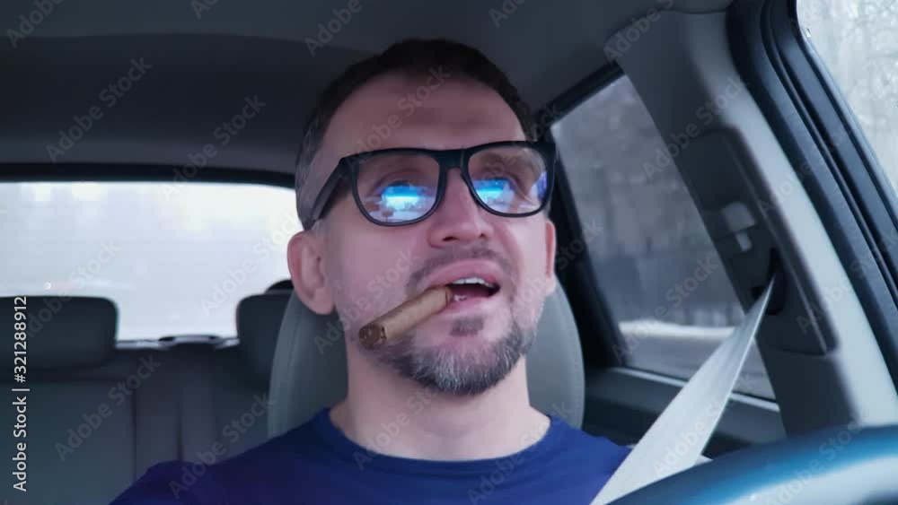 Caucasian man driving passenger car with cigar smiles and nods to music Caucasian man driving passenger car with cigar smiles and nods to music
