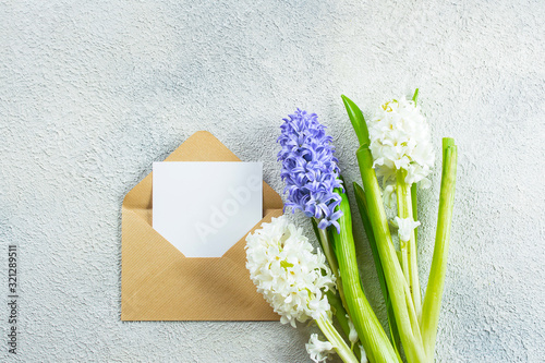 Mother's day Holiday Concept. Hyacinth flowers and empty card on light concrete background. Spring Greeting card. Flat lay, top view, copy space. Mockup concept.