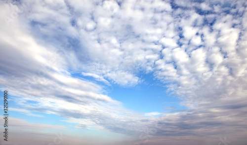 Beautiful panoramic sky landscape with white flying clouds extending over the skyline line