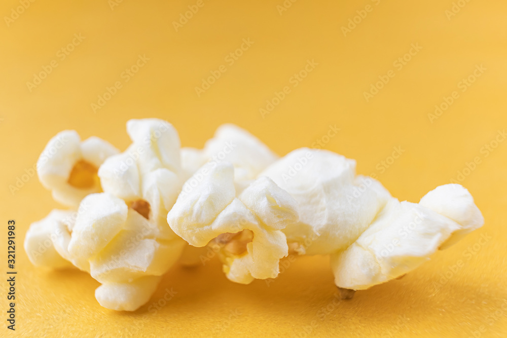 Obraz premium Close-up popcorn on a bright yellow background, macro photo. The concept of unhealthy delicious food, entertainment, a snack in the cinema. Copyspace.