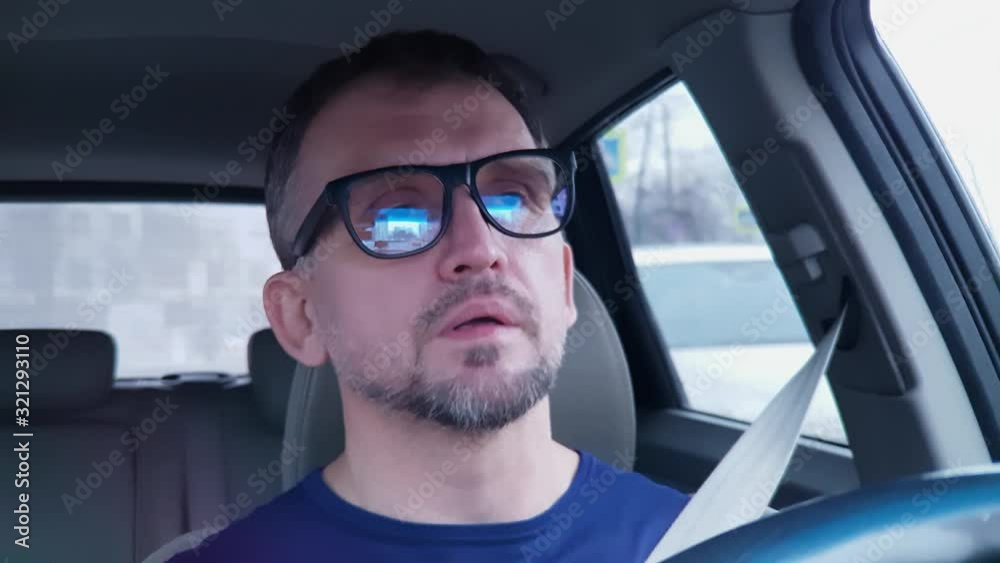 Quiet white man with beard driving passenger car. Strong reflection in his glasses Quiet white man with beard driving passenger car. Strong reflection in his glasses
