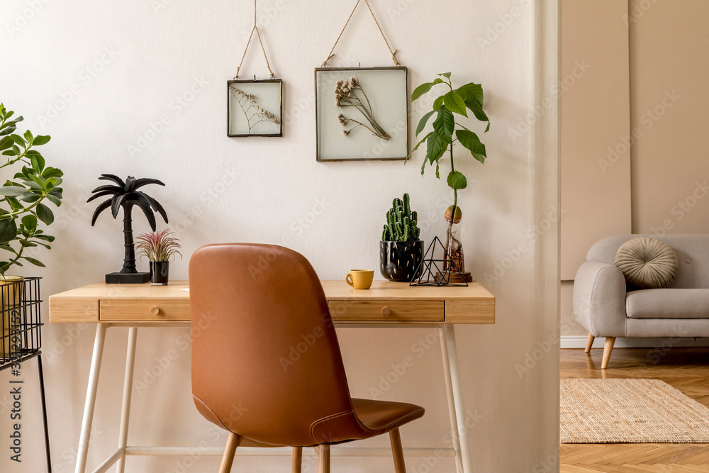 Fototapeta premium Interior design of scandinavian open space with mock up photo frames, wooden desk, gray sofa, cacti, books office and personal accessories. Stylish neutral home staging. Beige walls. Template.