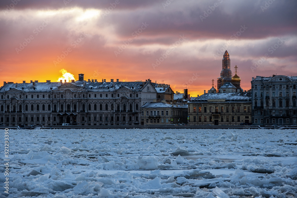 Fototapeta premium colorful dawn over the Palace embankment across the Neva river, covered with sharp ice floes