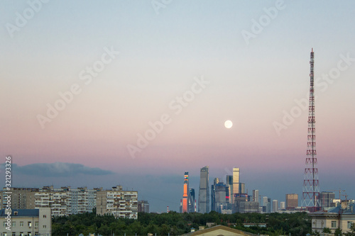 Moscow/ Russia - 16.06.2019: View of the old and modern city with skyscrapers against a dark evening sky with a full moon