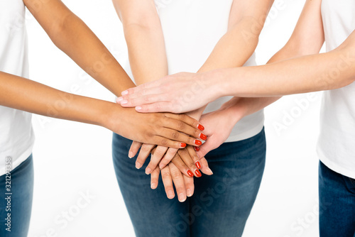 cropped view of multicultural women putting hands together isolated on white