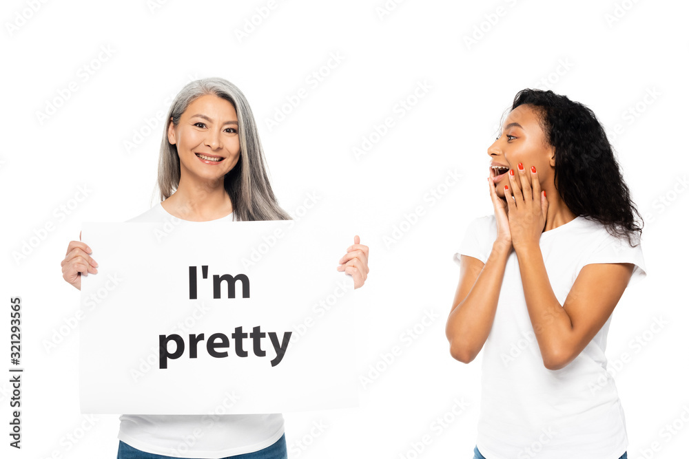 cheerful african american and asian women near i`m pretty placard isolated on white cheerful african american and asian women near i`m pretty placard isolated on white
