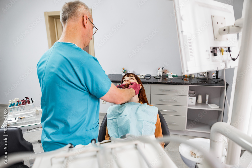 Obraz premium Professional senior man doctor dentist working with young girl patient in modern clinic