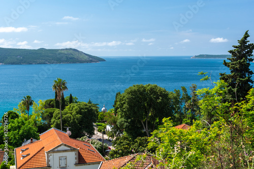 Seascape with tiled roofs of houses, yachts and forest. On a sunny day with blue sky.