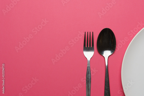 dieting and health care concept. top view of a fork, spoon and plate on pink dine table. flat lay. free copy space for your text