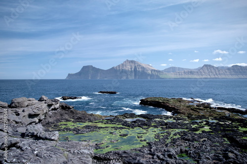 Horizontal scenery image of Faroese landscape with beautiful mountain and the North Atlantic Ocean nearby village Gjogv 