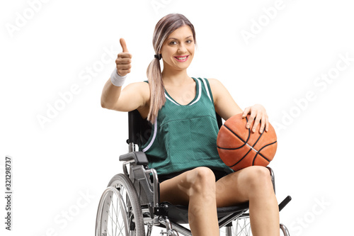 Young woman in a wheelchair holding basketball and showing thumbs up