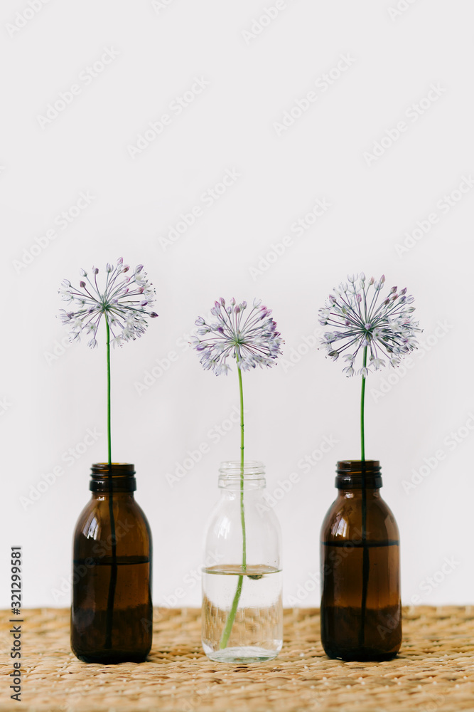 three purple round flowers in glass jars a wicker table three purple round flowers in glass jars a wicker table