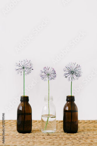three purple round flowers in glass jars a wicker table