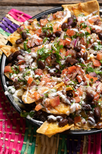 Mexican nachos with beans and pico de gallo sauce on wooden background
