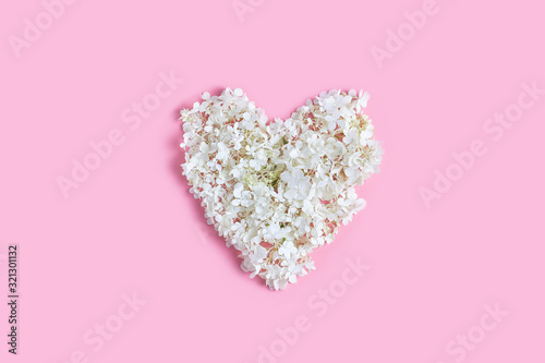 heart shape made of flowers on a pink background. flat lay, top view, valentines cards concept