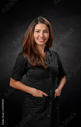Smiling woman in black spa uniform standing with hands in the pockets