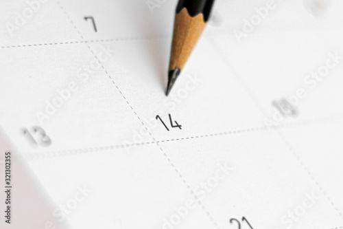 pencil point at date of february 14 on the calendar. - Valentine's Day concept.