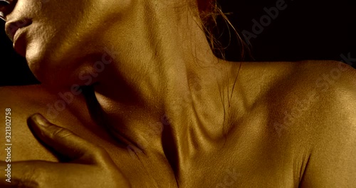 sensual excited woman is rubbing golden dye on skin of neck and shoulders, detail view photo