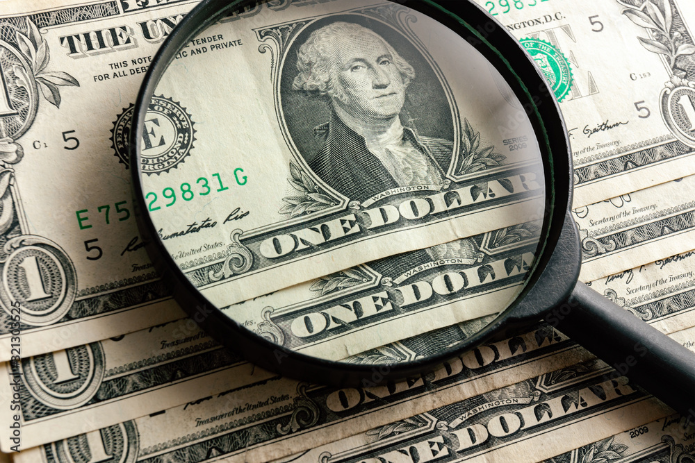 Enlarged portrait of D. Washington on one US dollar banknote through a magnifying glass. Several American dollar bills close up. Bundle of USA cash.
