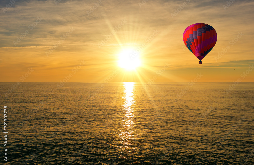 A hot air balloon over the sea at sunrise A hot air balloon over the sea at sunrise