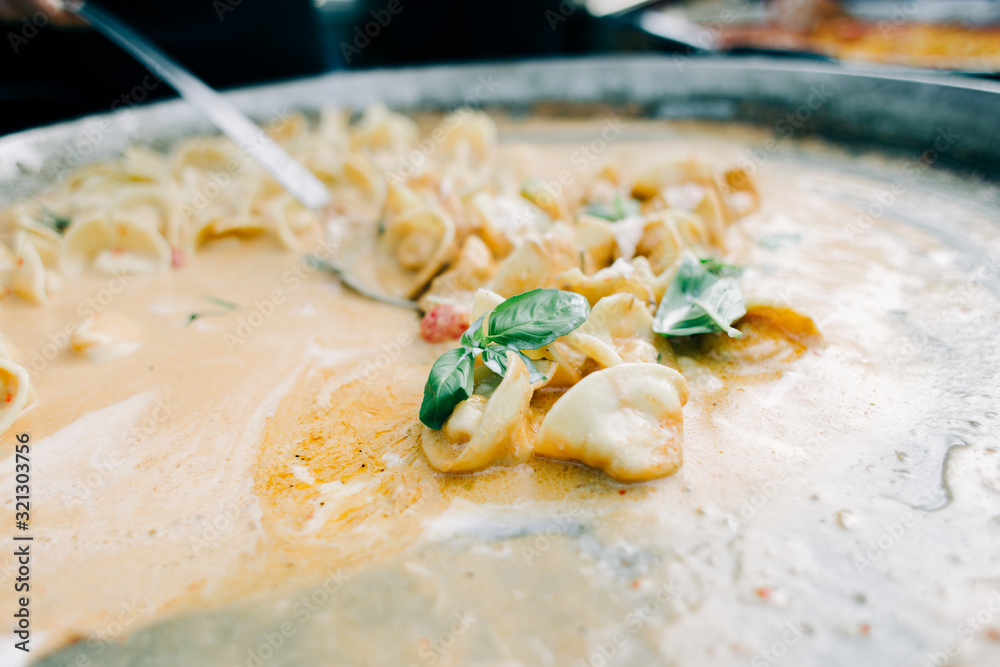 delicious ravioli with tomatoes and Basil in a creamy sauce, in a large frying pan, street food delicious ravioli with tomatoes and Basil in a creamy sauce, in a large frying pan, street food
