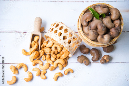 Roasted salted raw cashew nuts with Fresh cashew in spoon and  basket isolated on white wooden background,top view. photo