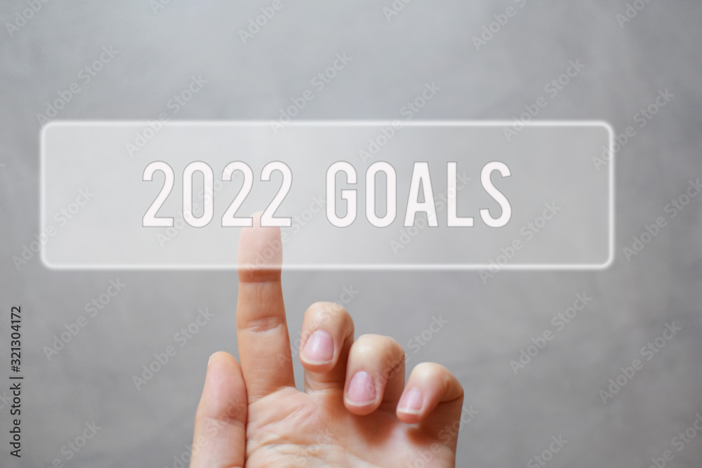 2022 goals - finger pressing grey transparent button on grunge virtual touchscreen interface. New year resolutions planning concept. 2022 goals - finger pressing grey transparent button on grunge virtual touchscreen interface. New year resolutions planning concept.