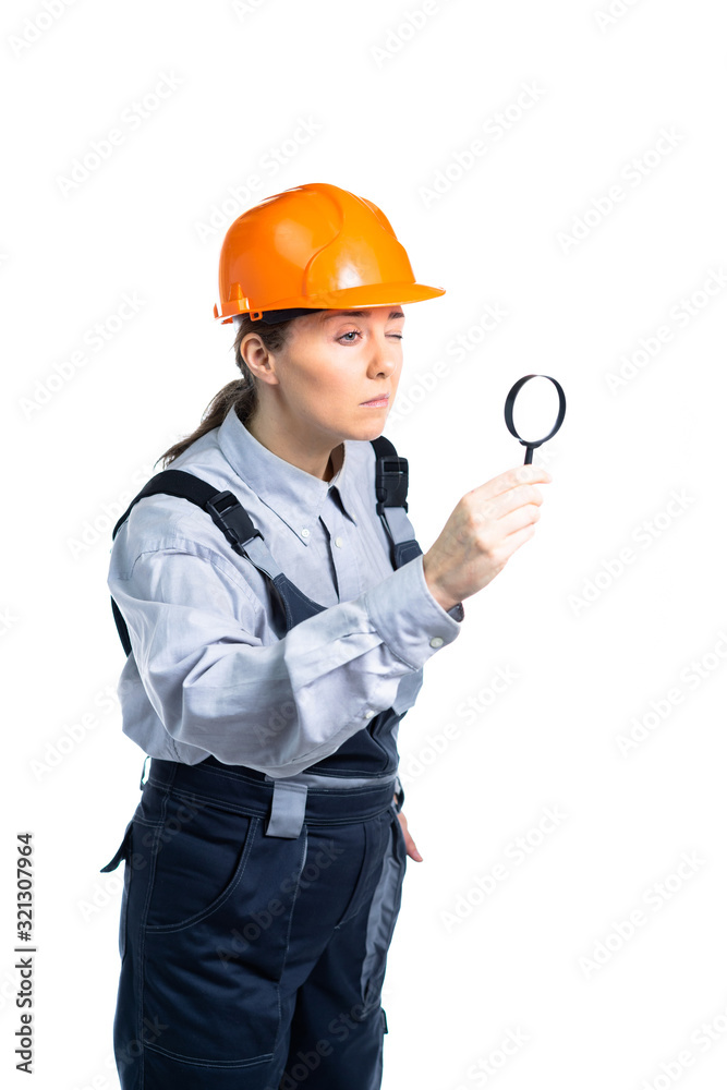 girl construction engineer examines something in a magnifying glass. Isolated girl construction engineer examines something in a magnifying glass. Isolated