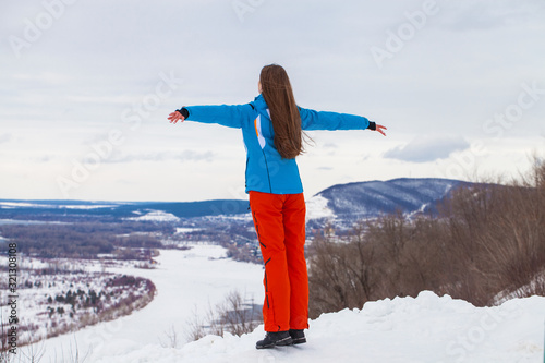 Young brunette woman in a ski suit posing on a hilltop