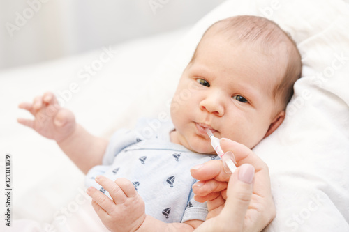 Принти на полотні Mother feeding newborn baby with liquid Vitamin K