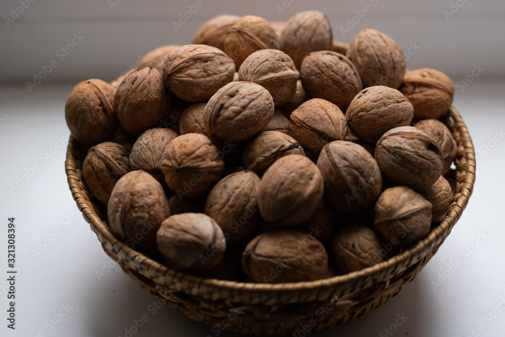 Small wicker basket filled with walnuts on a white background Small wicker basket filled with walnuts on a white background